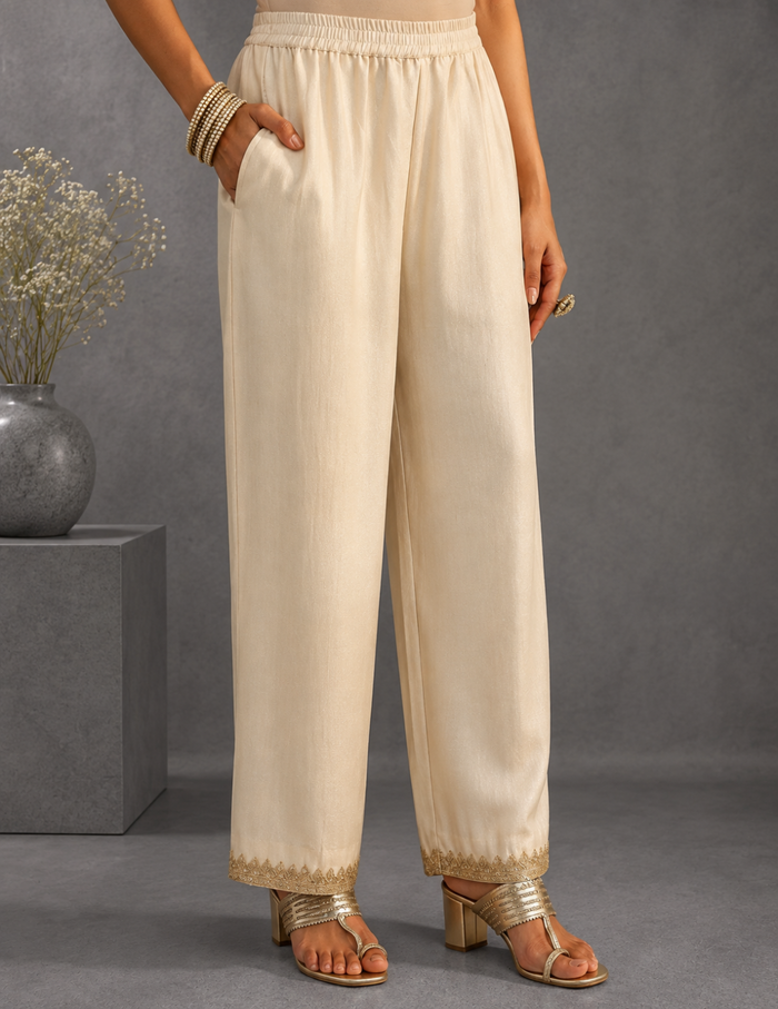 "An ivory embellished silk blend straight suit set featuring intricate detailing and a graceful dupatta, showcased against a simple grey background in an elegant side-profile pose."