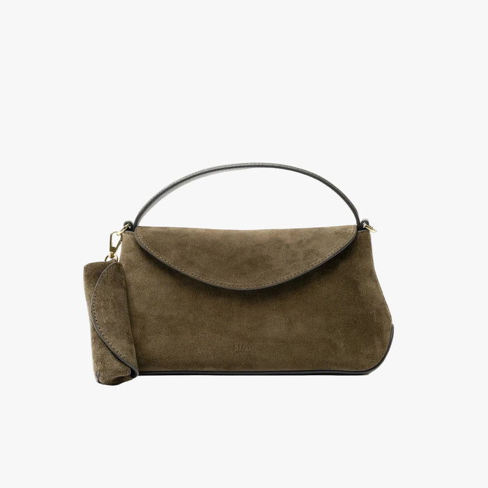 STOW London's Lipstick Case in Dark Green suede leather attached to the matching Mini East West bag on a light grey background featuring a gold-coated stainless steel clip