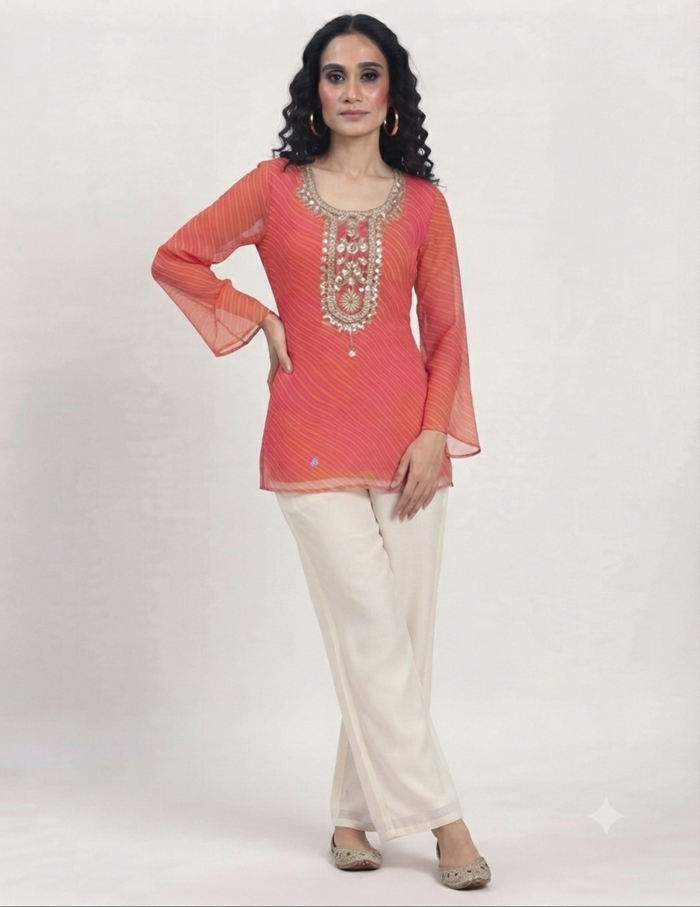 Model wearing a vibrant pink and orange leheriya tunic with detailed embroidery against a neutral background