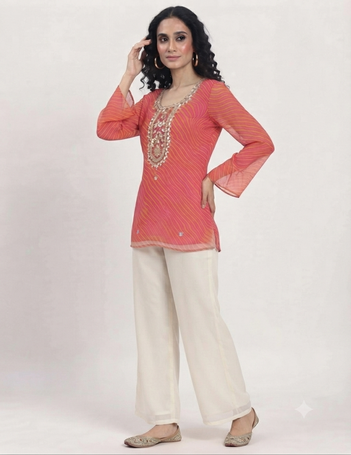 Model wearing a vibrant pink and orange leheriya tunic with detailed embroidery against a neutral background