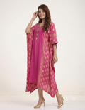A woman modeling a bright pink kaftan dress with gold floral prints and gold button detailing on the neckline, paired with gold high heels against a plain white studio background.