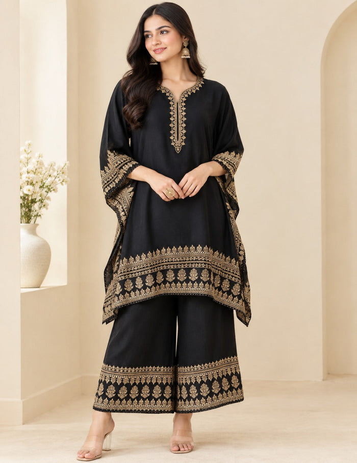 Model posing in an elegant black kaftan and palazzo set with detailed gold foil printing and embroidery against a neutral background.