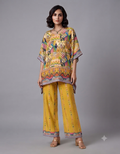 A female model posing in a vibrant yellow patterned kaftan top and matching wide-leg pants against a plain grey background.
